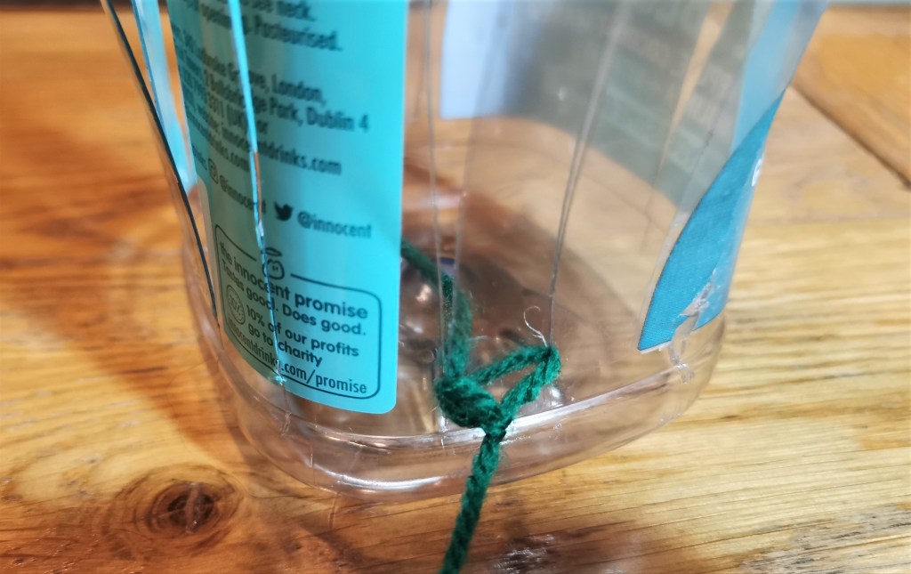 Yarn tied to bottle strip. Knot turned to the inside.